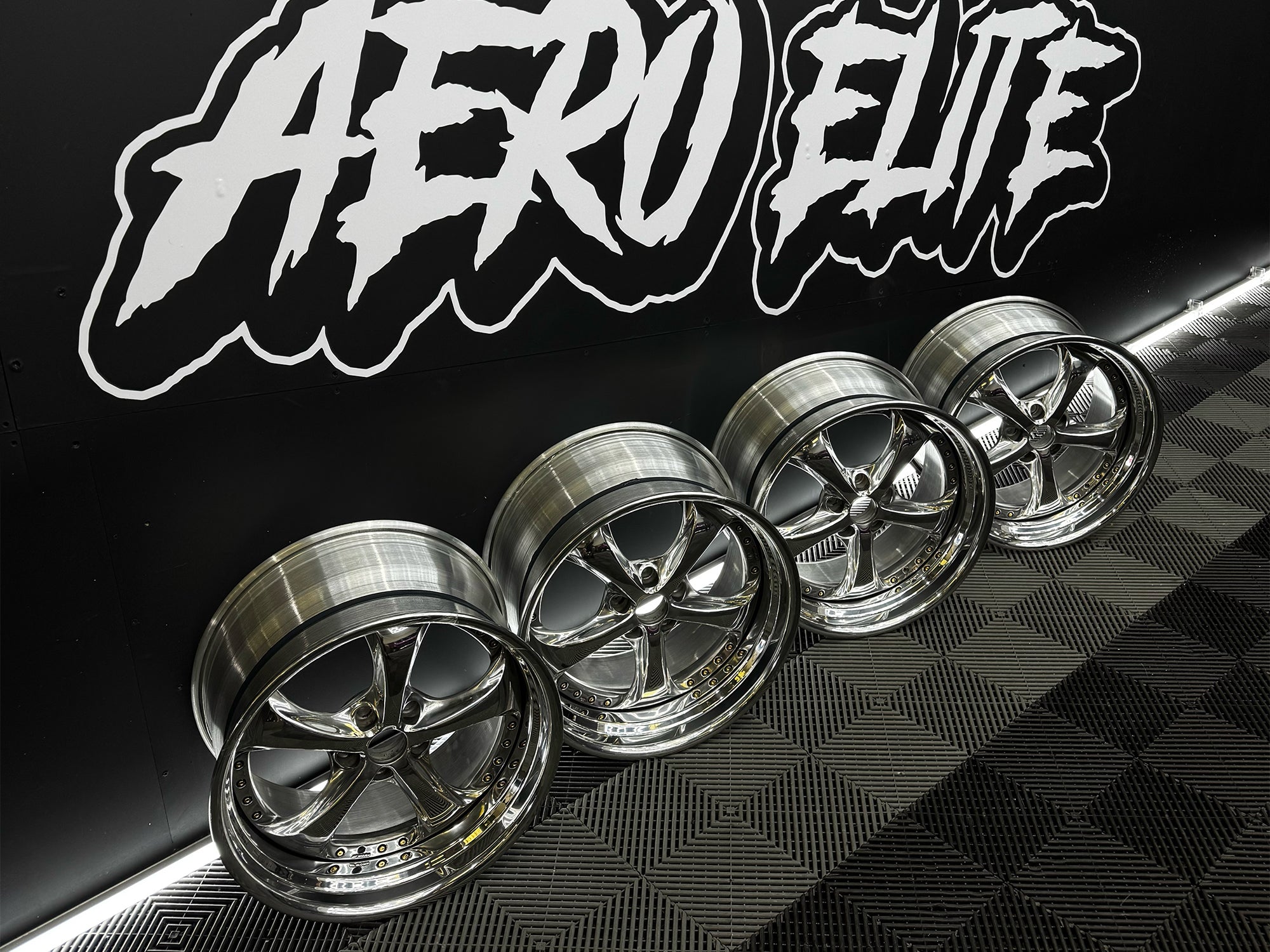 Set of chrome Work VSKF alloy wheels on a black and gray checkered background with 'Aero Elite' branding.
