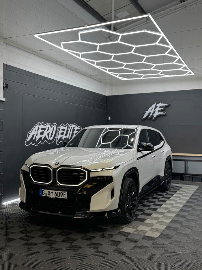 BMW XM G09 front three-quarter shot with full bodykit, lights on