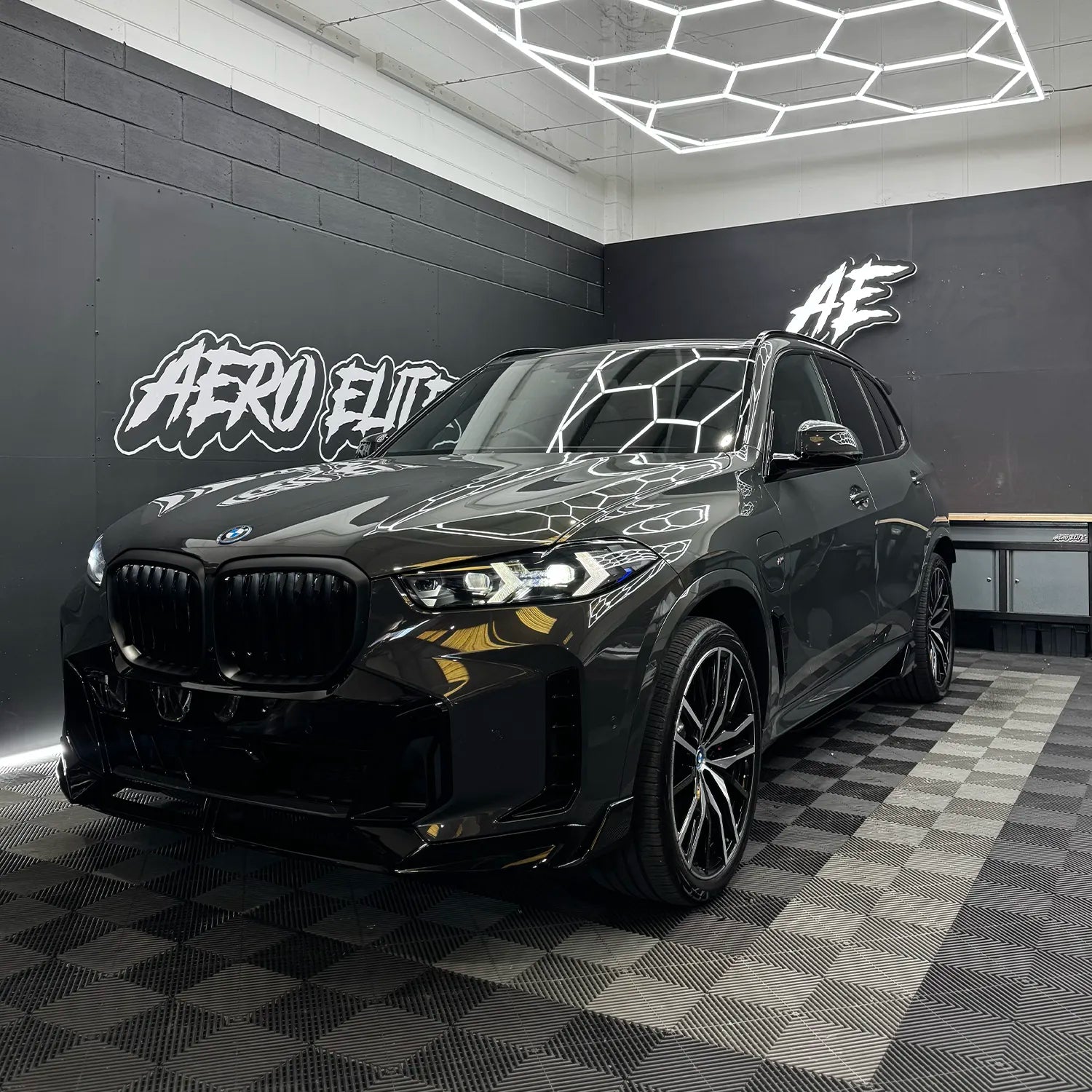 BMW G01 Facelift with a gloss black splitter kit freshly fitted, parked inside Aero Elite fitting bay.