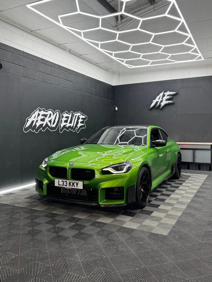 BMW M2 (G87) front three-quarter view after fitting black forged wheels, carbon side skirts and front splitter