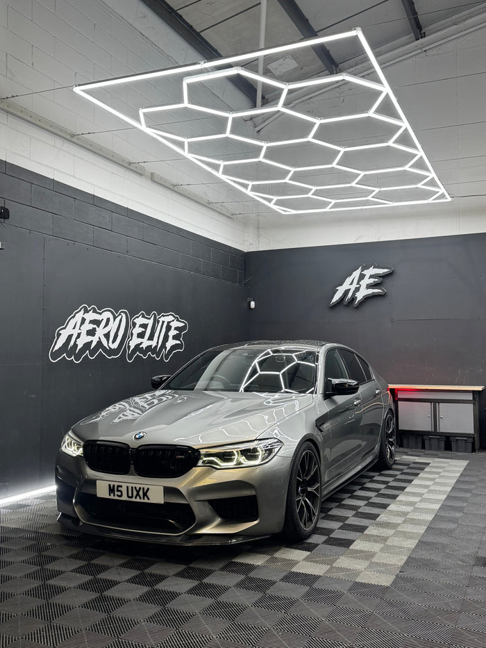 BMW M5 F90 Competition front three-quarter hero shot after lowering, carbon splitter and bodykit fitment