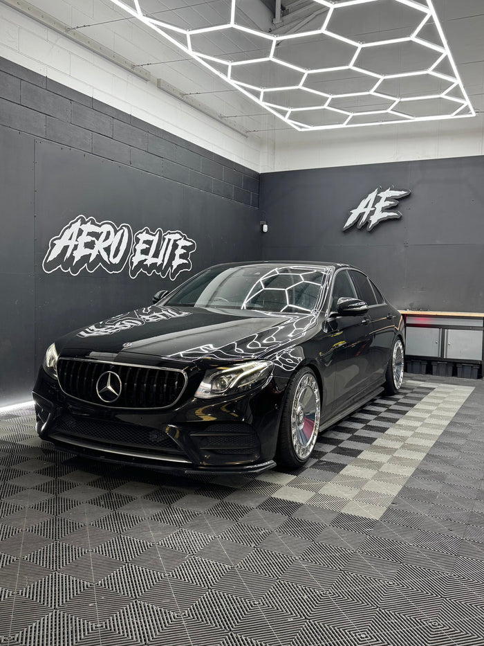 Mercedes-Benz E-Class W213 front three-quarter view after fitting new wheels, lowered suspension, Panamericana grille and front splitter